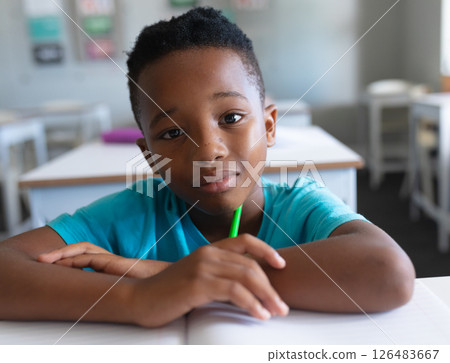 In school, African American boy holding pencil, looking thoughtful in classroom In school, African American boy holding pencil, looking thoughtful in classroom 126483667