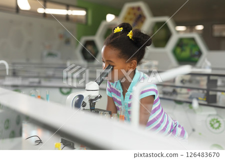 In school science lab, African American girl using microscope, exploring with curiosity, copy space 126483670