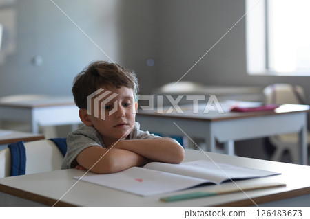 Young boy in school classroom reading book, looking thoughtful and focused, copy space 126483673
