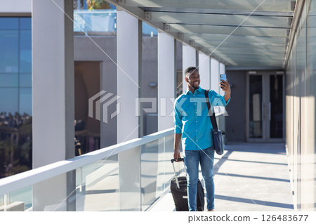 African American man walking with suitcase, taking selfie at modern office building, copy space African American man walking with suitcase, taking selfie at modern office building, copy space 126483677