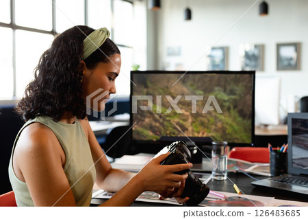 Woman reviewing camera in modern office, focusing on photography work, copy space Woman reviewing camera in modern office, focusing on photography work, copy space 126483685