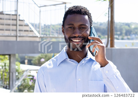 Talking on smartphone, businessman outdoors on sunny day, smiling brightly 126483722