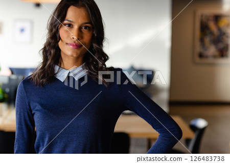 Confident woman in smart casual attire standing in modern office, smiling warmly 126483738