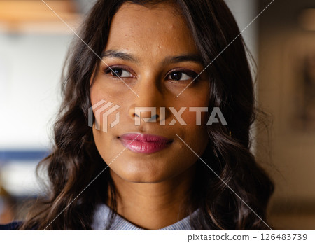 Confident woman with wavy hair looking away, thinking in modern office 126483739