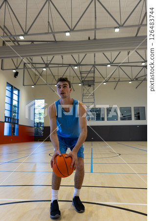 Young man in gym holding basketball, preparing to make shot 126483744