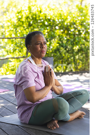 African American woman meditating on yoga mat outdoors, embracing tranquility 126483745