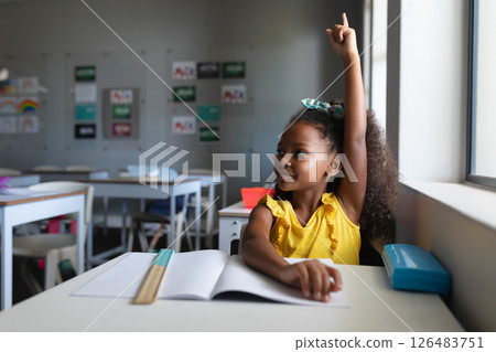 In school, young girl raising hand eagerly in classroom, ready to participate, copy space In school, young girl raising hand eagerly in classroom, ready to participate, copy space 126483751