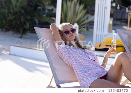 Relaxing on beach, woman in sunglasses enjoying drink on lounge chair 126483770
