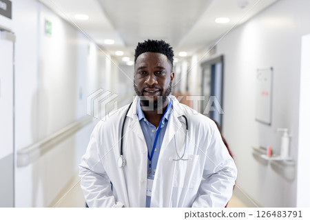 Doctor in hospital hallway wearing white coat and stethoscope, confidently smiling Doctor in hospital hallway wearing white coat and stethoscope, confidently smiling 126483791