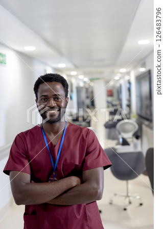 Smiling healthcare professional in scrubs standing confidently in hospital corridor 126483796