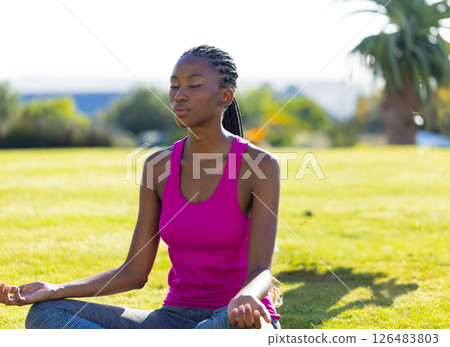 African American woman meditating on grass in backyard, enjoying peaceful moment 126483803
