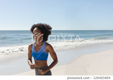 Smiling woman jogging on beach, enjoying sunny day and ocean breeze, copy space 126483804