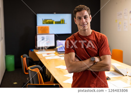 Confident man in office standing with arms crossed, smiling at camera 126483806