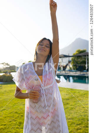 Relaxing by pool, woman enjoying sunny day with refreshing drink in hand 126483807