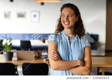 Smiling woman in smart casual attire standing confidently in modern office, copy space 126483814