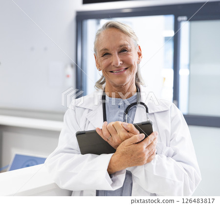 Smiling female doctor holding tablet in hospital, ready to assist patients Smiling female doctor holding tablet in hospital, ready to assist patients 126483817