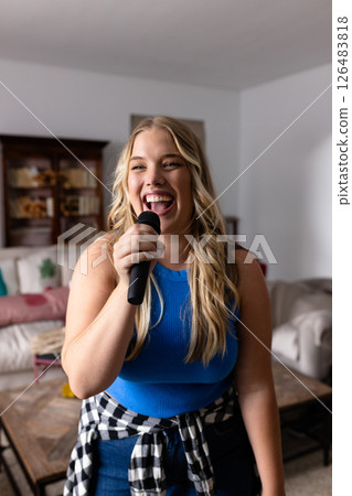 Woman singing with microphone at home, enjoying karaoke with friends Woman singing with microphone at home, enjoying karaoke with friends 126483818