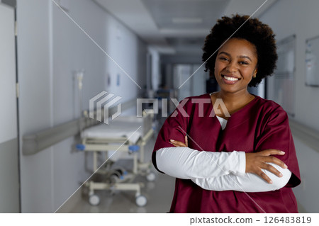 Smiling nurse in hospital hallway crossing arms, exuding confidence and warmth, copy space Smiling nurse in hospital hallway crossing arms, exuding confidence and warmth, copy space 126483819