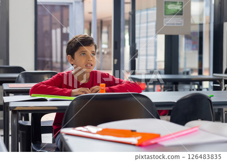 In school, young boy in red shirt attentively listening in classroom In school, young boy in red shirt attentively listening in classroom 126483835