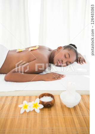 Woman relaxing at spa, enjoying massage with flower petals on back 126483863