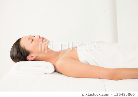 Relaxing at spa, serene asian woman resting on massage table with towel pillow Relaxing at spa, serene asian woman resting on massage table with towel pillow 126483866