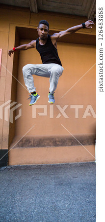 Man performing parkour jump in urban setting, showcasing agility and strength Man performing parkour jump in urban setting, showcasing agility and strength 126483868