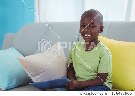 Smiling boy holding tablet on couch, enjoying technology at home Smiling boy holding tablet on couch, enjoying technology at home 126483900