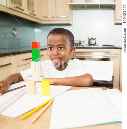 Boy building block tower at kitchen table, focusing on creativity and learning 126483903