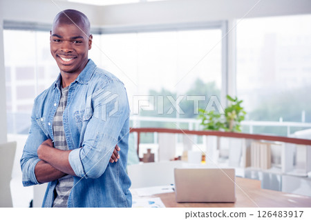 Confident businessman in office crossing arms and smiling near laptop, copy space 126483917