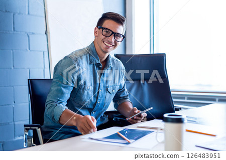 Smiling man in denim shirt using tablet and writing notes at office desk, copy space 126483951