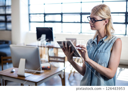 Blonde woman using tablet in modern office, focusing on digital work, copy space 126483953