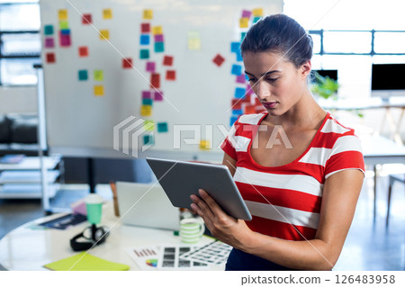 Focused woman using tablet in modern office with colorful sticky notes, copy space Focused woman using tablet in modern office with colorful sticky notes, copy space 126483958