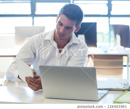 Young professional using tablet and laptop at modern office, focusing on work, copy space Young professional using tablet and laptop at modern office, focusing on work, copy space 126483961