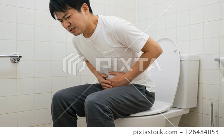 A man in a white T-shirt endures stomach pain in the toilet A man in a white T-shirt endures stomach pain in the toilet 126484053