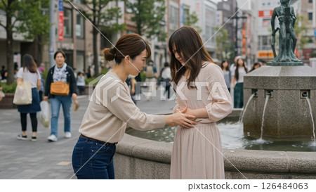 A woman caring for a woman with stomach pain in the square A woman caring for a woman with stomach pain in the square 126484063