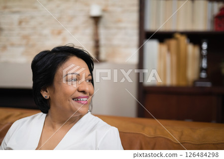 Smiling woman relaxing on couch at home, enjoying peaceful moment indoors, copy space Smiling woman relaxing on couch at home, enjoying peaceful moment indoors, copy space 126484298