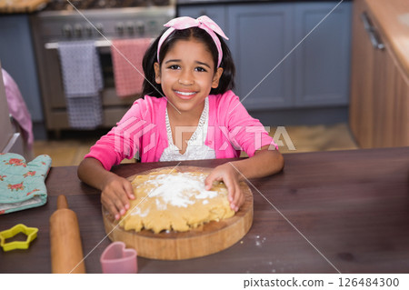 Smiling girl baking dough at home, enjoying fun kitchen activity Smiling girl baking dough at home, enjoying fun kitchen activity 126484300