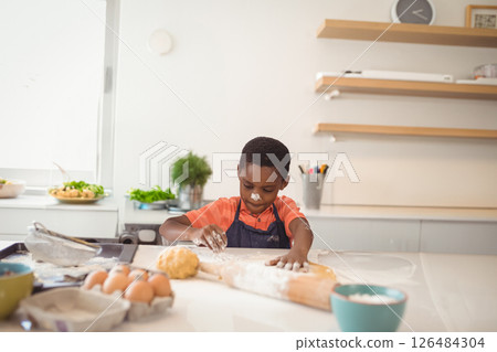 Young boy baking at home, concentrating while kneading dough on kitchen counter, copy space 126484304