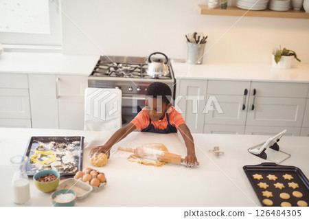 Young boy baking cookies in kitchen, rolling dough with concentration, copy space 126484305
