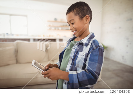 Smiling boy using smartphone at home, enjoying technology in living room, copy space Smiling boy using smartphone at home, enjoying technology in living room, copy space 126484308
