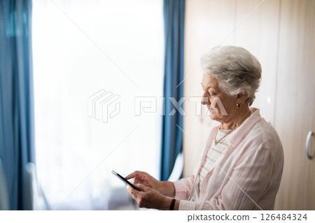 Elderly woman using smartphone at home, staying connected with family, copy space 126484324