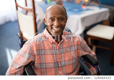 Elderly man in wheelchair smiling warmly at retirement home dining area Elderly man in wheelchair smiling warmly at retirement home dining area 126484325