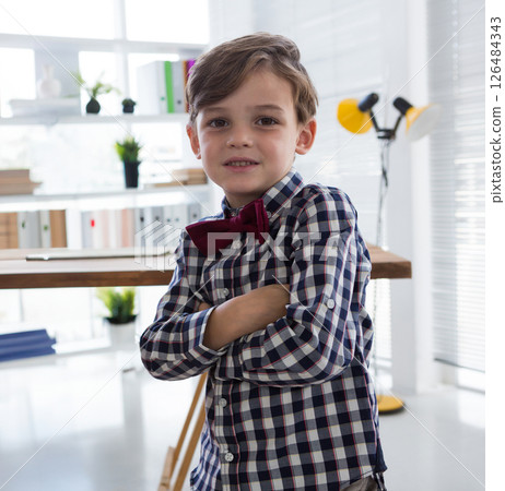 Confident boy in checkered shirt crossing arms in modern office setting Confident boy in checkered shirt crossing arms in modern office setting 126484343