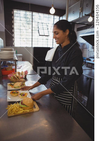 Chef preparing delicious gourmet burgers and fries in modern cafe kitchen, copy space Chef preparing delicious gourmet burgers and fries in modern cafe kitchen, copy space 126484356