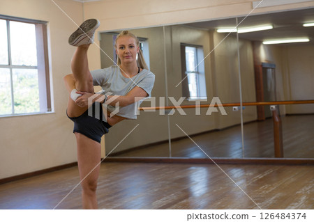 Young woman practicing dance moves in studio, showing flexibility and focus, copy space 126484374