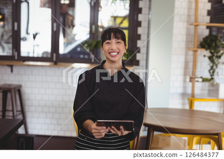 Smiling chef holding tablet in modern cafe, ready to take orders Smiling chef holding tablet in modern cafe, ready to take orders 126484377
