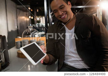Smiling man holding tablet at modern restaurant, enjoying evening dining experience, copy space Smiling man holding tablet at modern restaurant, enjoying evening dining experience, copy space 126484400