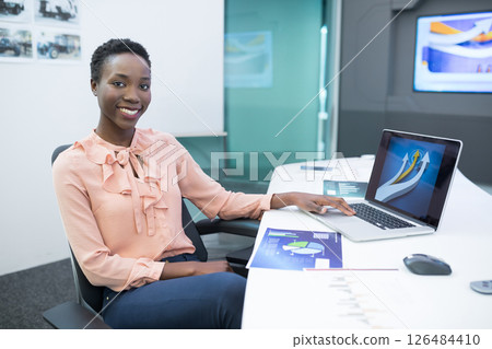 Smiling businesswoman using laptop in modern office, analyzing digital charts, copy space Smiling businesswoman using laptop in modern office, analyzing digital charts, copy space 126484410