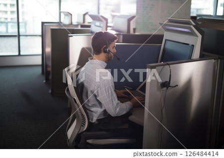 Man using headset and computer in modern office cubicle, focusing on work 126484414
