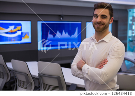 Confident businessman in modern office standing with arms crossed, smiling at camera, copy space Confident businessman in modern office standing with arms crossed, smiling at camera, copy space 126484418
